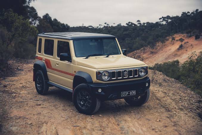 Suzuki Samurai on a dirt track — cream body with red stripe, restored to original character